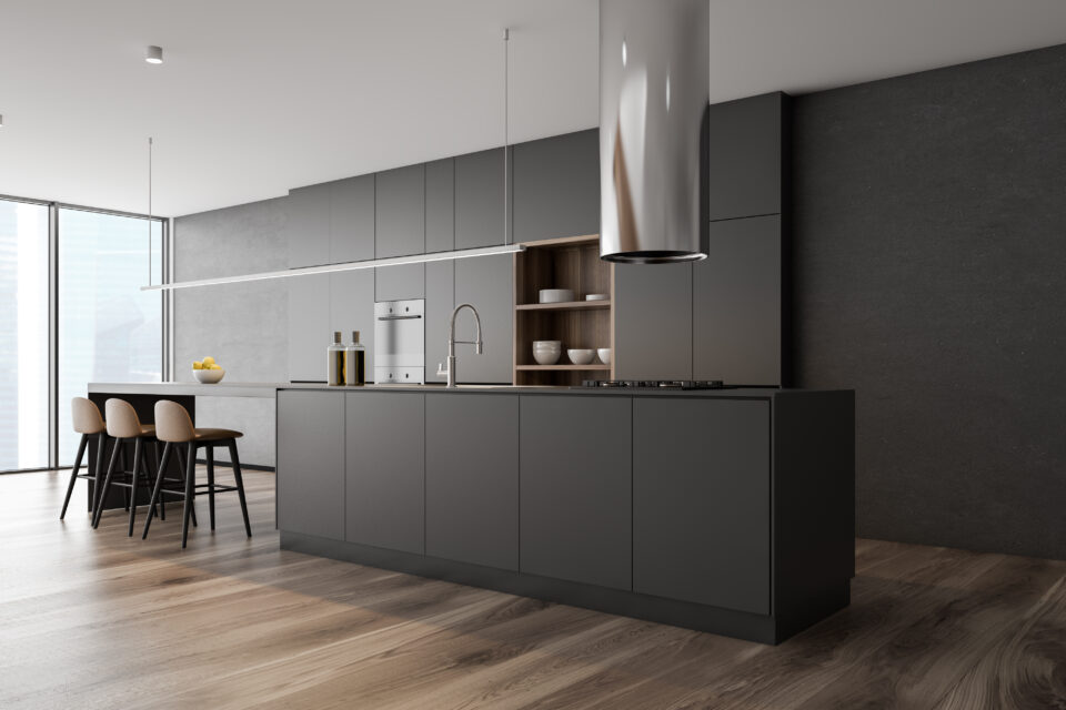 Corner of panoramic kitchen with concrete walls, wooden floor, dark gray island with built in sink and cooker, gray cupboards and bar with stools. 3d rendering